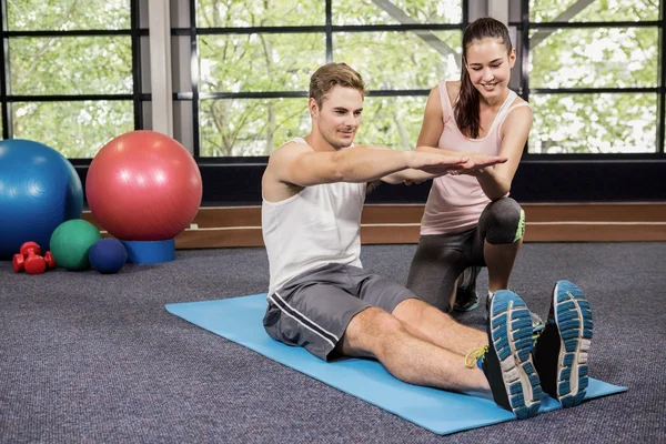 Trainer assisting man with abdominal crunches — Stock Photo, Image