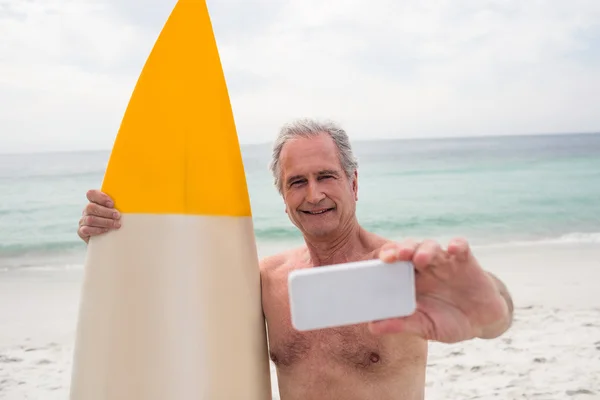 Homem sênior com prancha de surf tirando selfie — Fotografia de Stock