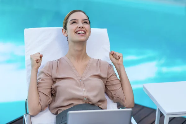 Donna eccitata con computer portatile vicino alla piscina — Foto Stock