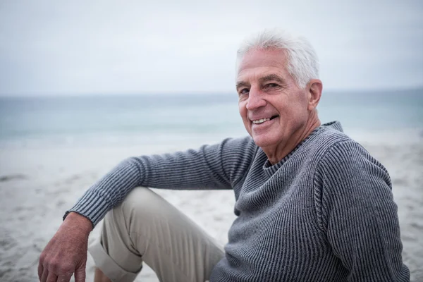 Щасливий старший чоловік сидить на пляжі — стокове фото