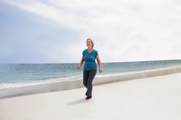 Senior vrouw joggen op strand — Stockfoto