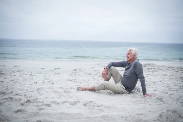 Doordachte gepensioneerde man zit op strand — Stockfoto