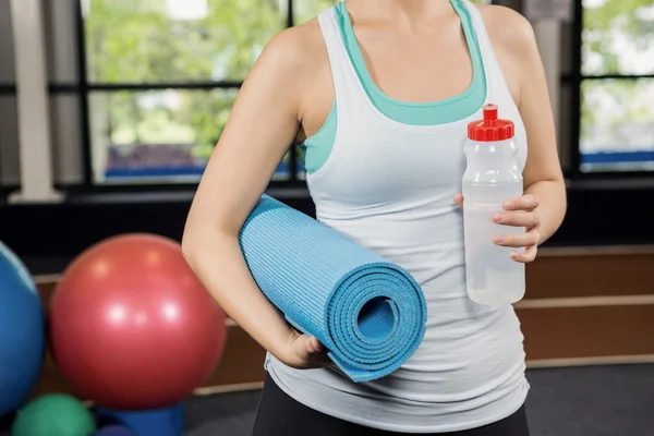 Mulher segurando tapete de exercício e garrafa — Fotografia de Stock