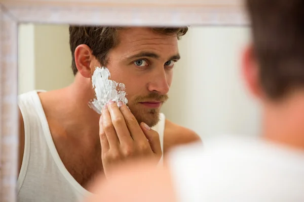 Homem aplicando espuma de barbear no rosto — Fotografia de Stock