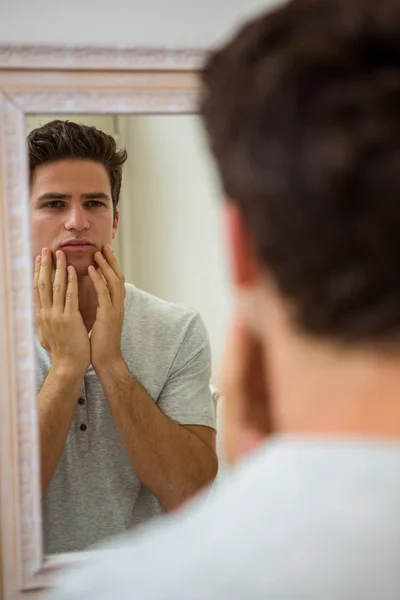 Человек проверяет свою кожу в ванной комнате — стоковое фото