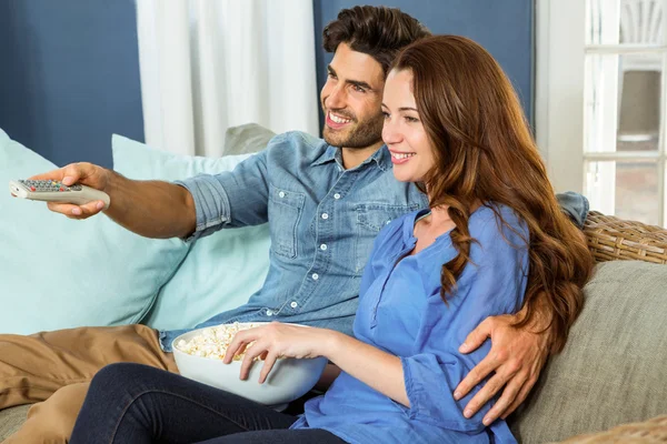 Pareja teniendo palomitas de maíz viendo televisión —  Fotos de Stock