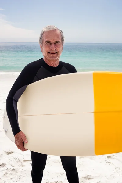 Senior en combinaison tenant une planche de surf — Photo