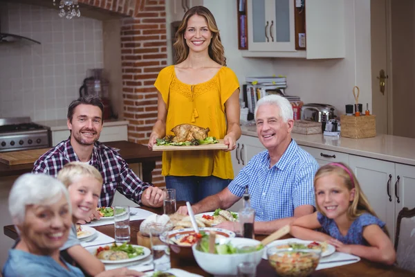 Família sorridente na mesa de jantar com a mãe de pé — Fotografia de Stock