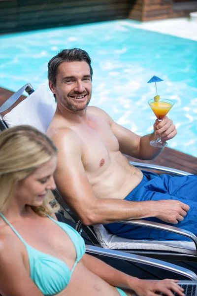 Couple sitting on sun lounger near pool — Stock Photo, Image