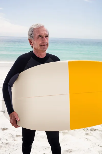 Старший человек в гидрокостюме, держащий доску для серфинга — стоковое фото