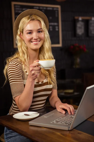 Woman drinking coffee and using laptop — Stock Photo, Image