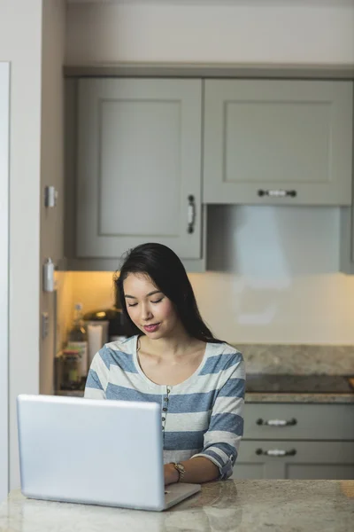 Kvinna med bärbar dator i köket — Stockfoto