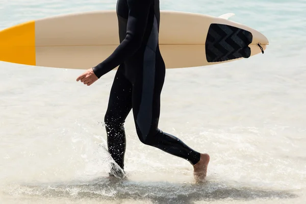 Surfista caminando en la playa con tabla de surf — Foto de Stock