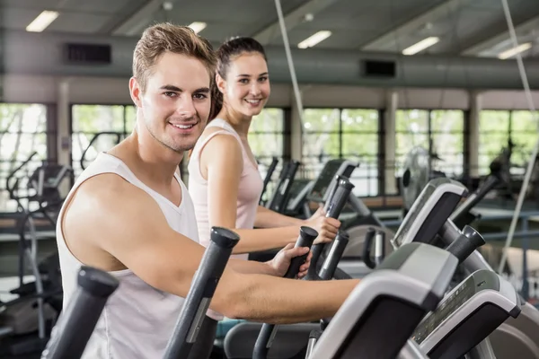 Mujer y hombre haciendo ejercicio en la máquina elíptica — Foto de Stock