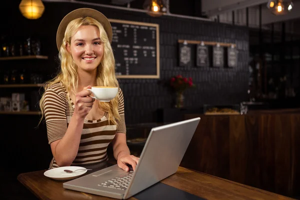 Femme buvant du café et utilisant un ordinateur portable — Photo