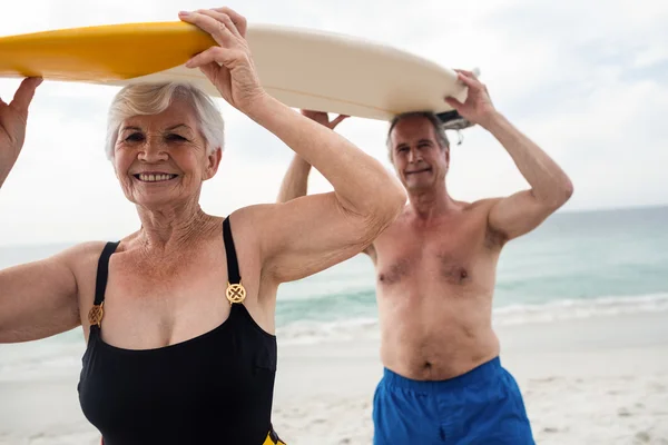 Coppia anziana che trasporta tavola da surf — Foto Stock