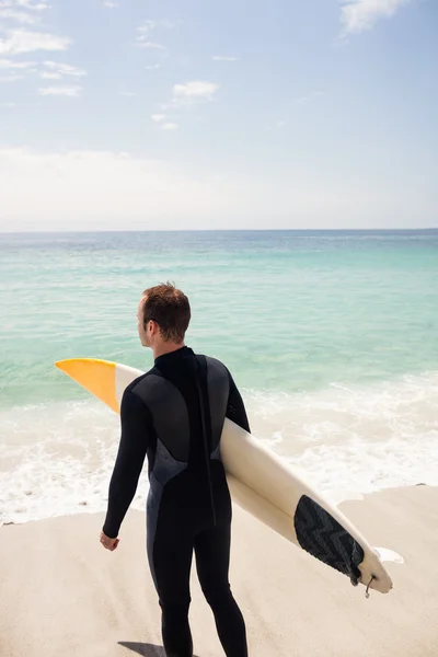 Surfista com prancha em pé na praia — Fotografia de Stock