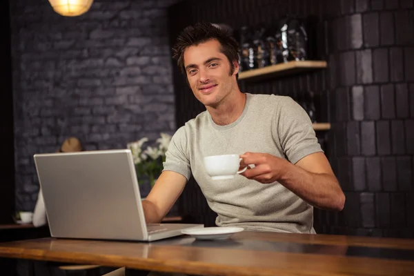 Человек с помощью ноутбука и пить кофе — стоковое фото