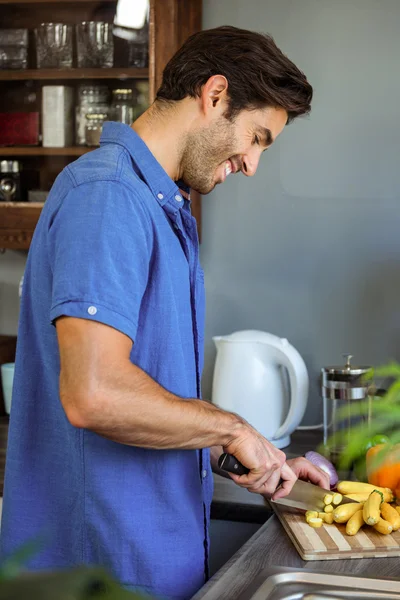 Человек режет овощи на кухонном столе — стоковое фото