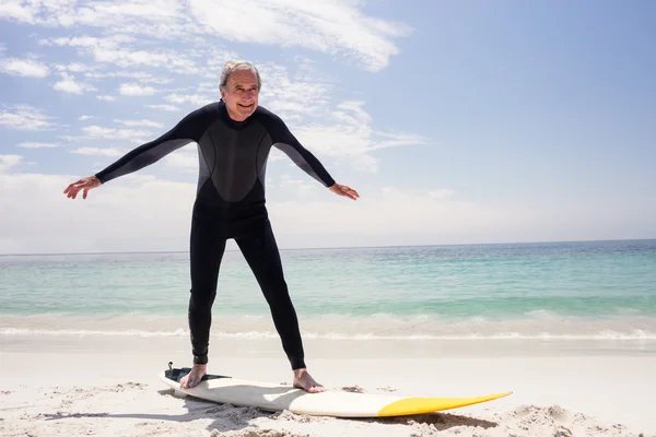 Senior en combinaison debout sur planche de surf — Photo