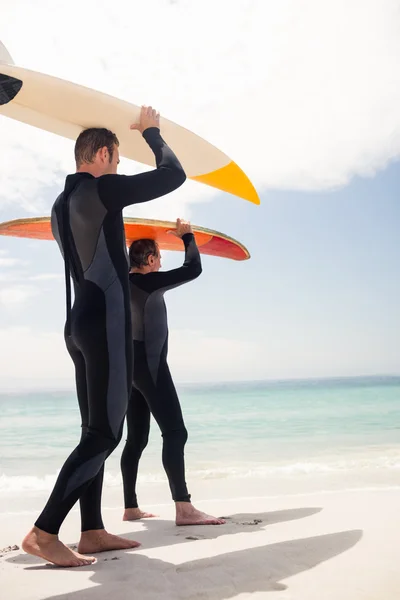 Padre e hijo llevando tabla de surf —  Fotos de Stock