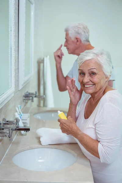 Senior woman applying cream — Stock Photo, Image