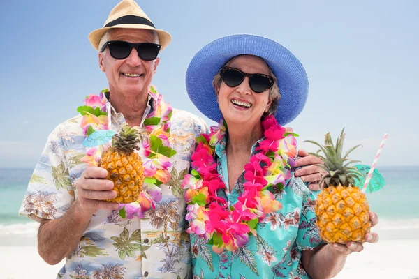 Старша пара носить гірлянду і тримає ананасові коктейлі — стокове фото