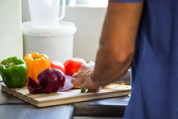 Man hugga grönsaker på köksbänken — Stockfoto