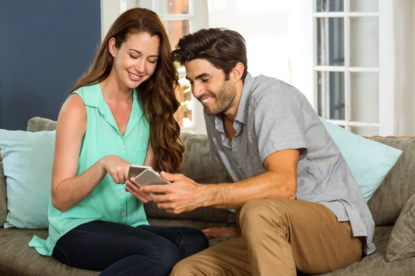 Par söker på telefon och ler — Stockfoto