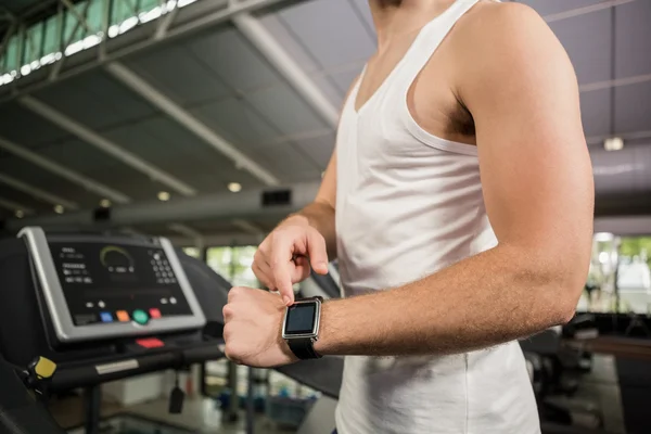 男人在跑步机上使用智能手表 — 图库照片