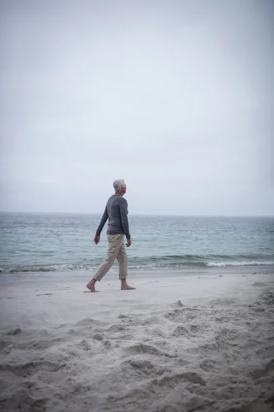 Senior geht am Strand spazieren — Stockfoto