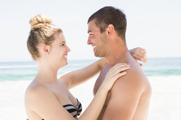 Lachende paar omarmen op het strand — Stockfoto