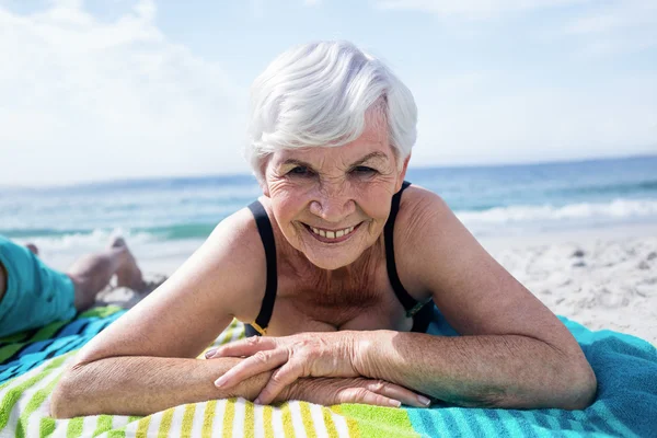 Äldre kvinna liggande på stranden — Stockfoto