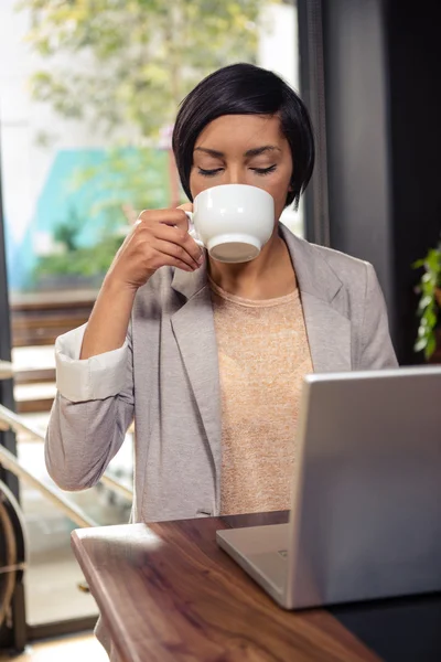 Woman drinking coffee and using laptop — Stock Photo, Image