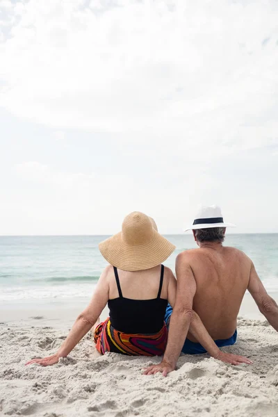 Casal de idosos sentado na praia — Fotografia de Stock