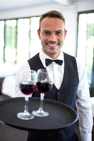 Garsona kırmızı şarap ile tepsi tutarak — Stok fotoğraf