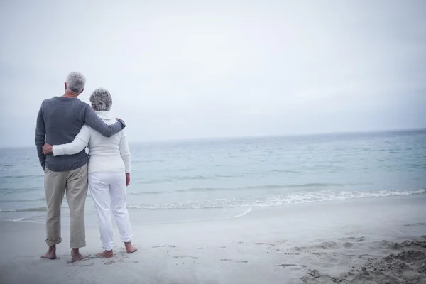Старша пара обіймається на пляжі — стокове фото