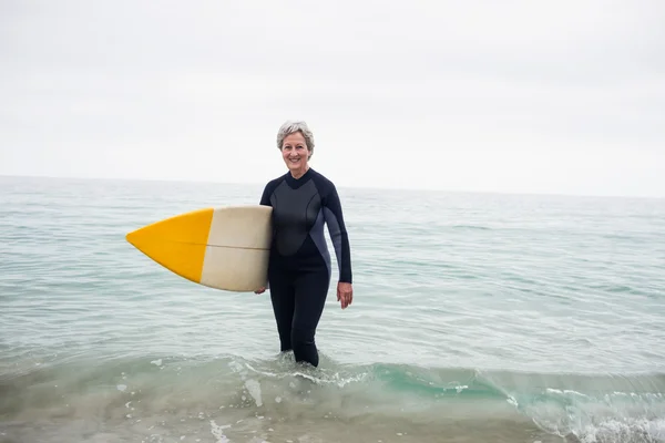 Senior vrouw in water met surfboard — Stockfoto