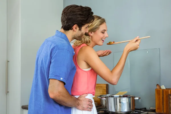Couple tasting meal in kitchen at home — Stock Photo, Image