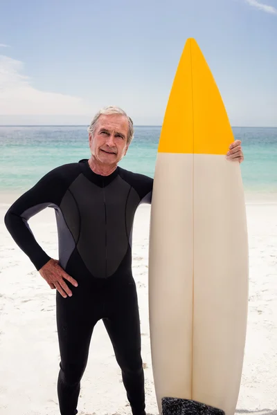 Senior en combinaison tenant une planche de surf — Photo