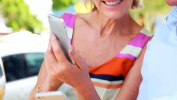 Pareja sonriente usando teléfonos inteligentes — Vídeo de stock