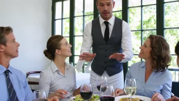 Официант приносит тарелки деловым людям — стоковое видео