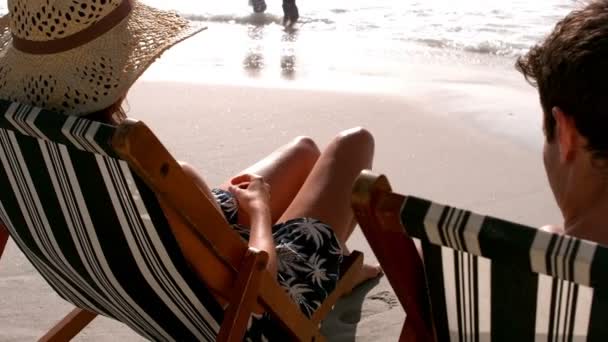 Пара сидить на сонячному кріслі під час засмагання — стокове відео