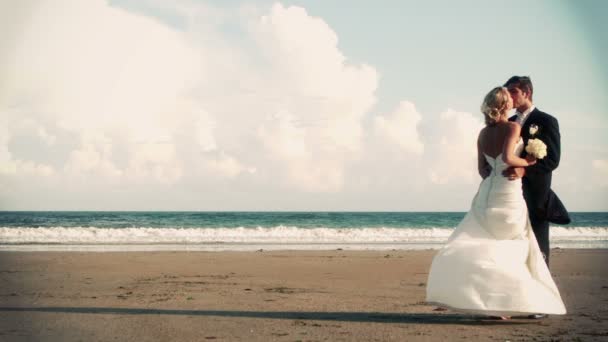 Jonggehuwde paar zoenen op het strand — Stockvideo