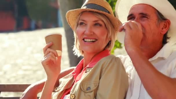 Pareja sonriente sentada en un banco — Vídeos de Stock