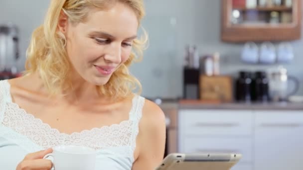 Женщина пьет кофе и использует планшет — стоковое видео