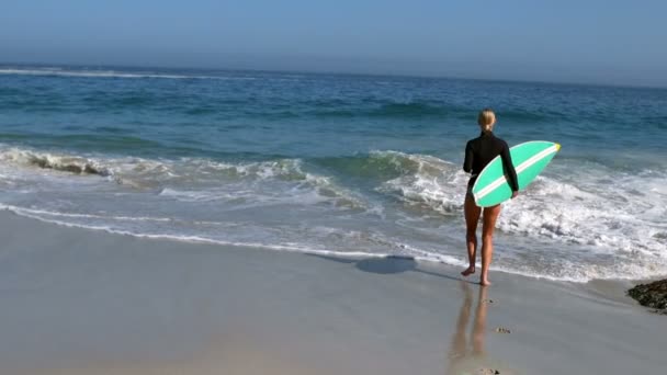 Женщина бежит в воду с доской для серфинга — стоковое видео
