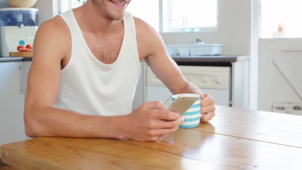Мужчина пьет кофе и пользуется смартфоном — стоковое видео