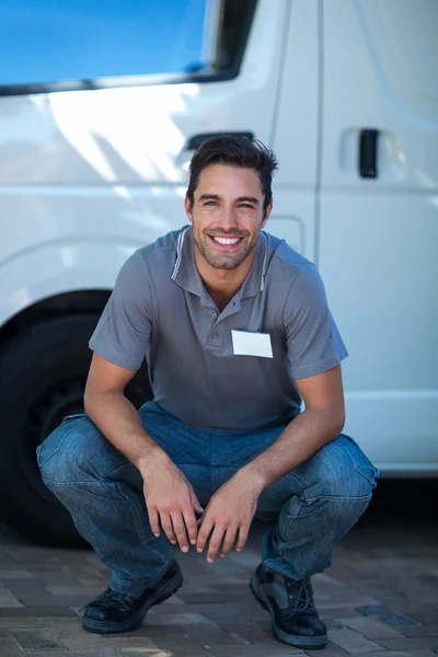 Levering man crouching door van — Stockfoto