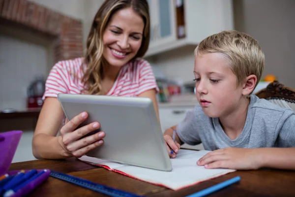 Mamma att hjälpa sonen med läxor hemma — Stockfoto